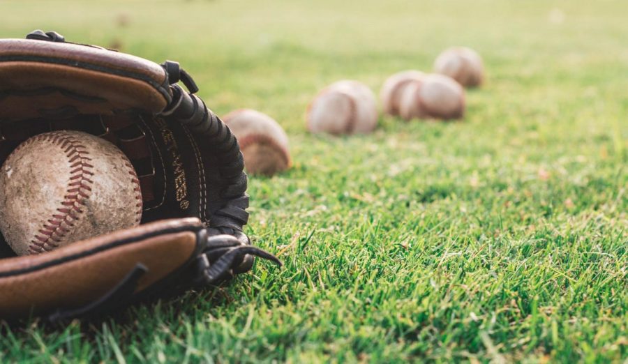 Baseball mitt laying down on grass with baseball inside. (Photo Courtesy: Pexels.com)