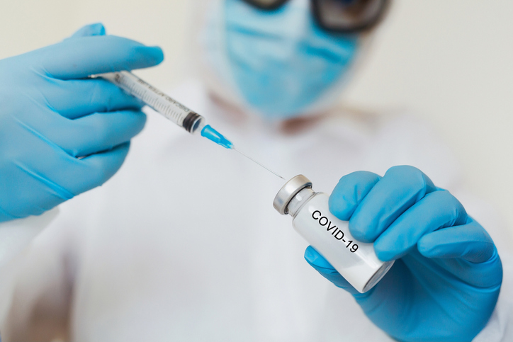 Covid-19 vaccine illustration of doctor with vaccine vial. Credits to Isparmo on Getty Images.