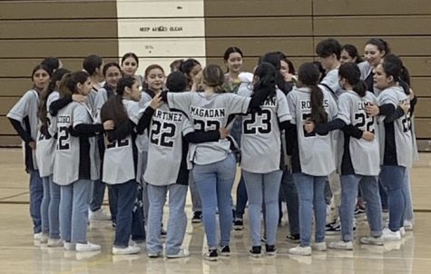 The hip hop team is gathered in the center of the gym in their routine huddle where they chant there usual cheer after every practice and performance.