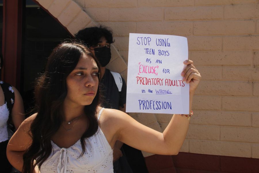 Giamae Villalobos stands in front of the counselors office holding a protest sign.  