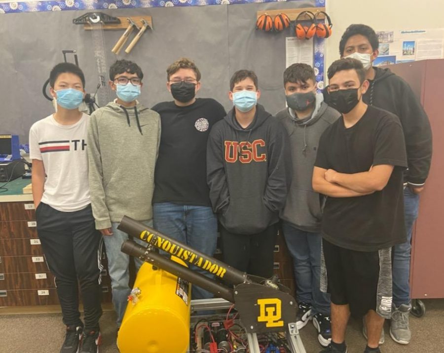 The Don Lugo Robotics Team stands next to the T-shirt cannon. This special robot is displayed during events such as football games where T-shirts are launched toward students in the audience. This year we are working on rebuilding the T-shirt launcher, says Mr. Engstrom.