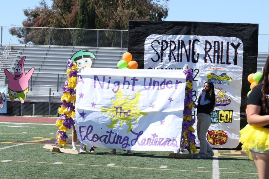 Students from ASB are seen holding up the poster that reveals the 2022 Prom theme at the  Spring rally. 
